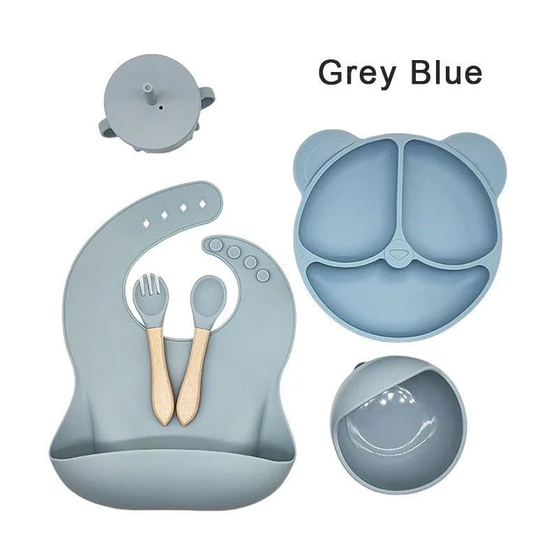 Set of grey blue silicone utensils and plates on a white background