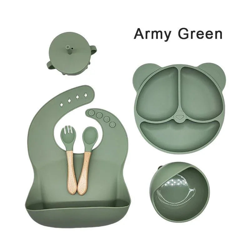 Set of green silicone utensils and plate with bear design on a white background
