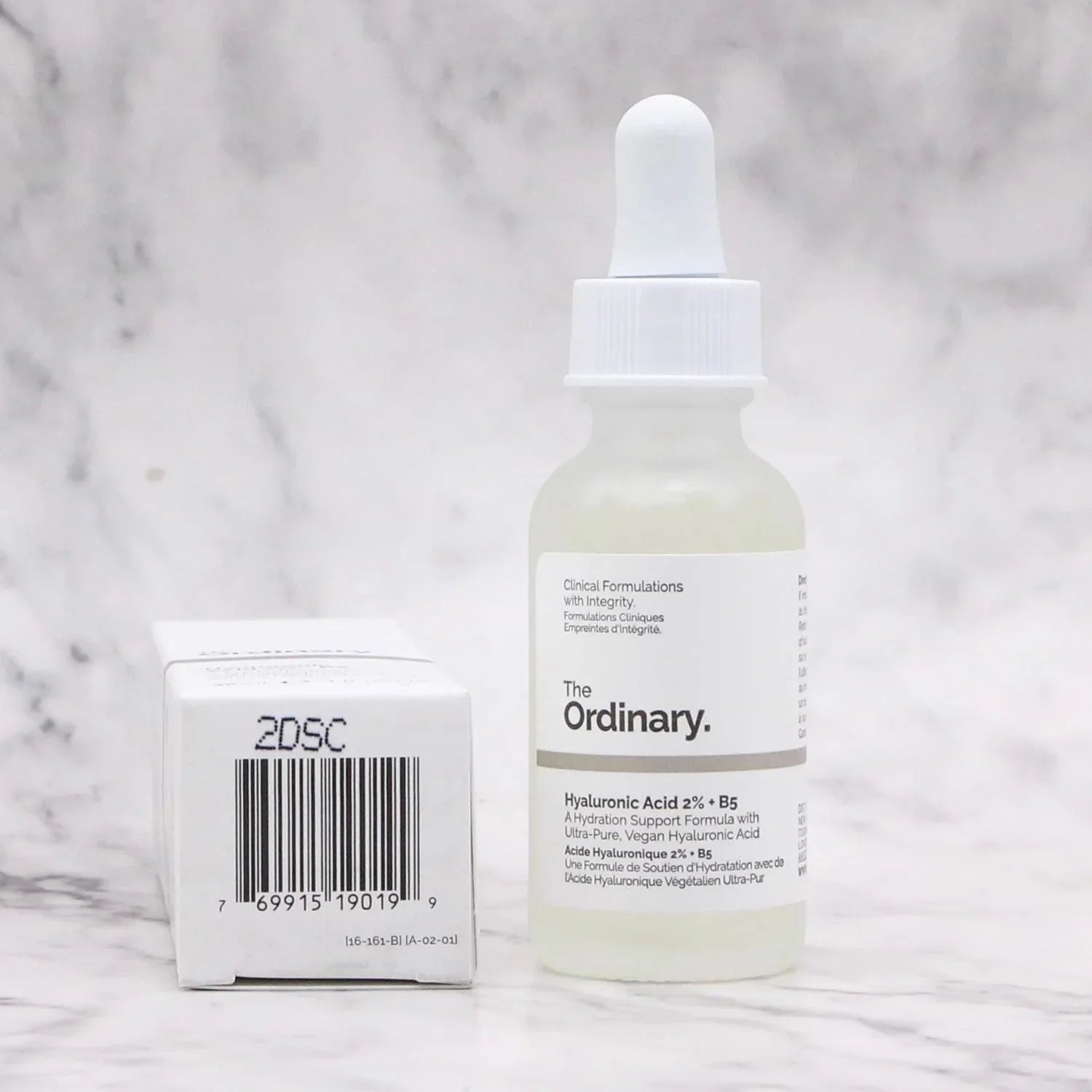Bottle of 'The Ordinary' skincare serum with dropper on a marble background