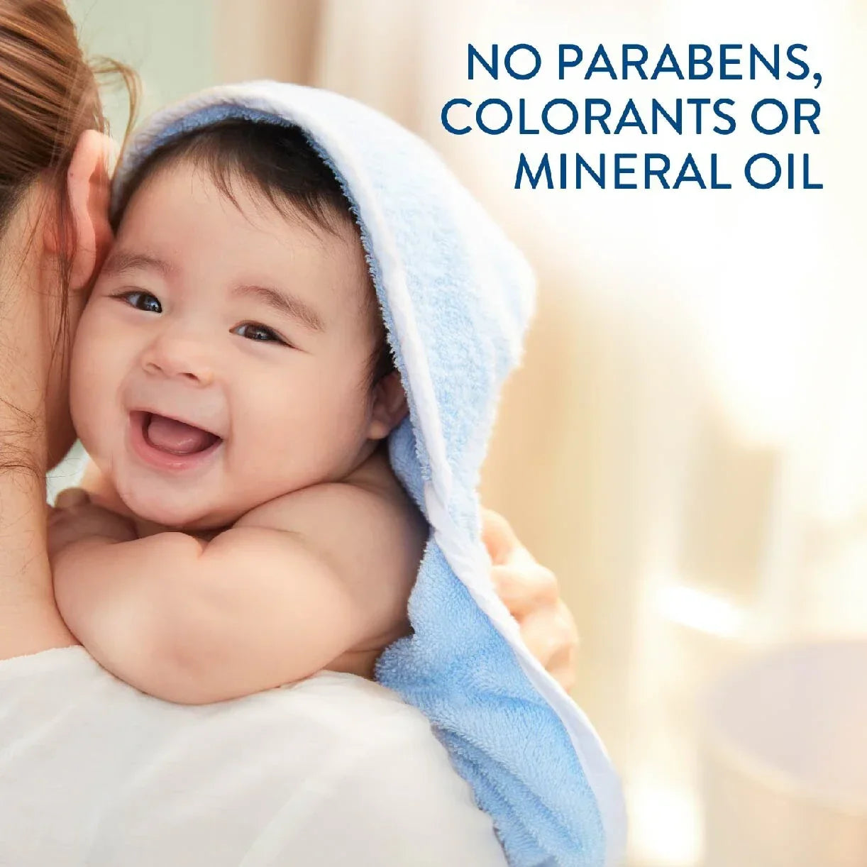 Baby wrapped in a towel being held by a person with text about product ingredients.